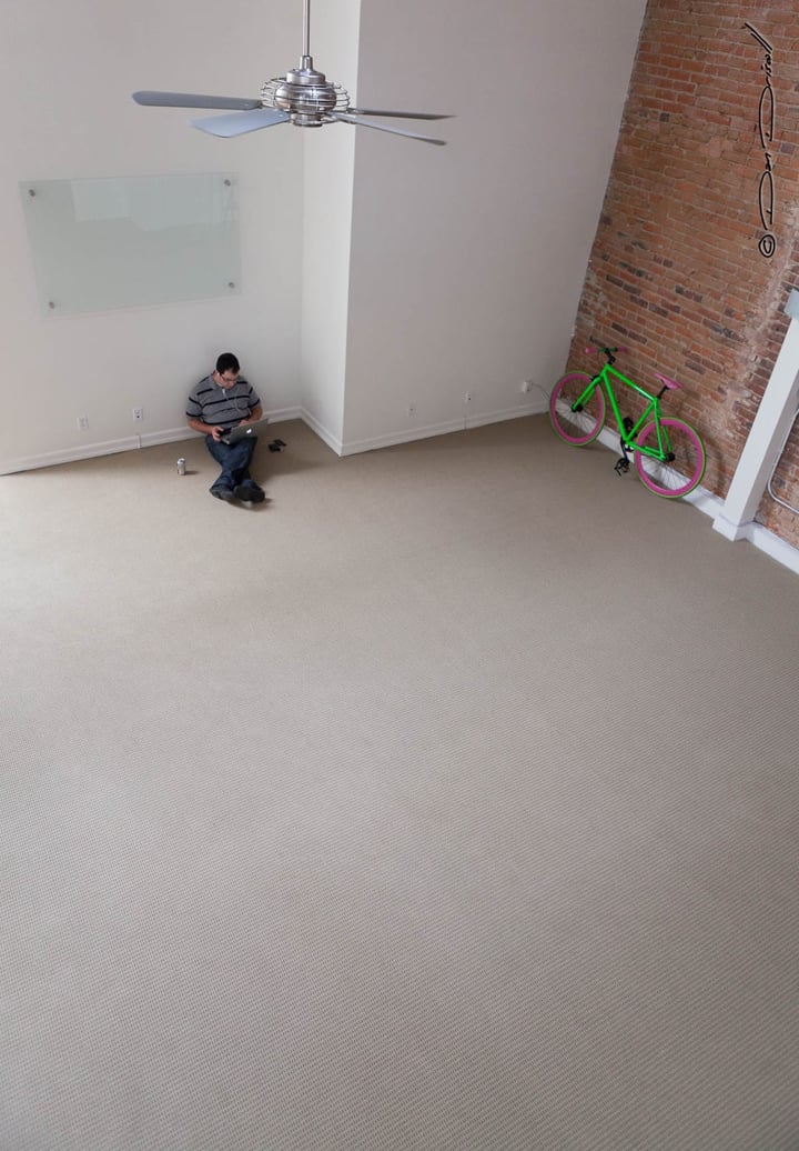 Matthew sitting in a big empty room next to a bright green bik.