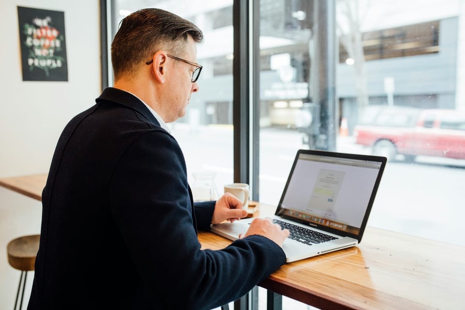 Image of a man at a coffee shop on his laptop. Photo by LinkedIn Sales Solutions on Unsplash.